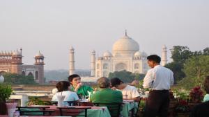 un grupo de personas sentadas en mesas frente a un edificio en Hotel Saniya Palace inn, en Agra