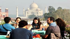 Un gruppo di persone seduti a un tavolo di fronte al taj mahal di Hotel Saniya Palace inn ad Agra
