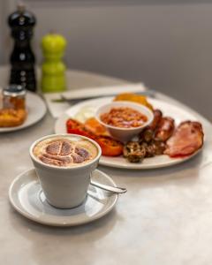 a table with a cup of coffee and a plate of food at Ramada Hotel & Suites by Wyndham Coventry in Coventry