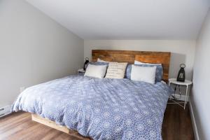Location Tourisme Estrie - Oberge du Village في ماجوج-اورفورد: غرفة نوم مع سرير مع اللوح الأمامي الخشبي