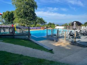 a swimming pool with a fence and tables and chairs at Idyllic Entire Chalet in Bideford Bay holiday Park near Clovelly in Bideford