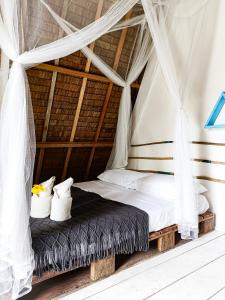 a bed in a tent with white sheets and pillows at Mao Mao surf in General Luna