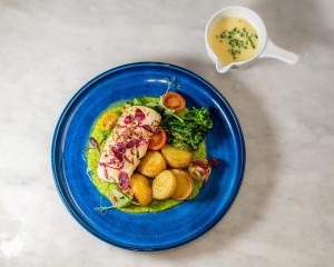 a blue plate of food with fish and potatoes and a cup of soup at Ramada Hotel & Suites by Wyndham Coventry in Coventry +49 photos