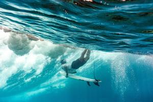 Un uomo che cavalca un'onda su una tavola da surf in acqua di Mao Mao surf a General Luna