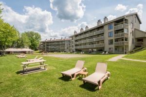 a group of chairs and tables in front of a building at Location Tourisme Estrie - Oberge du Village in Magog-Orford
