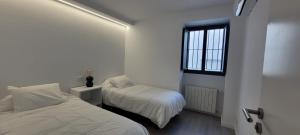 a white bedroom with two beds and a window at COZY & MODERN APARTMENT HOMBRE DE PIEDRA in Seville