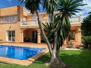 una casa con una piscina y una palmera en Beach Villa Costanera in Marbella, en Marbella
