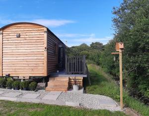 Gwalchmai的住宿－Shepherds Hut with hot tub on Anglesey North Wales，小木屋设有门廊和甲板