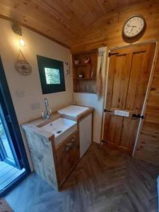 a bathroom with a sink and a clock on the wall at Shepherds Hut with hot tub on Anglesey North Wales in Gwalchmai