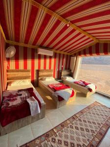 a bedroom with two beds and a large window at Mountain Magic Camp Wadi Rum in Wadi Rum
