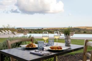 a table with two glasses of wine and food on it at I Carusi Relais in Noto