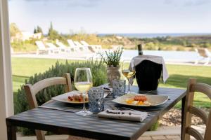 a table with two plates of food and glasses of wine at I Carusi Relais in Noto