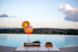 a drink sitting on a table next to a pool at I Carusi Relais in Noto