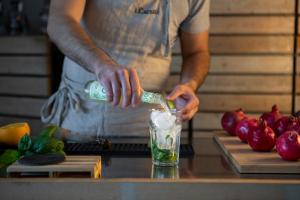 a man pouring a drink into a glass on a counter at I Carusi Relais in Noto