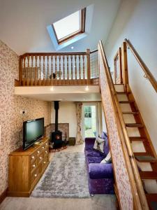 a living room with a staircase and a tv at Cosy 2 bed cottage on Dartmoor , Near Ivybridge in Plymouth