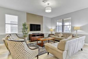 a living room with a couch and a tv at Tropical Nights - 8 bed ChampionsGate Resort family pool home in Davenport