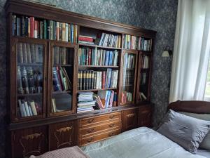 a large wooden book shelf filled with books at Narvan Maatilamajoitus Helenan Kanat ja Kammarit in Vesilahti