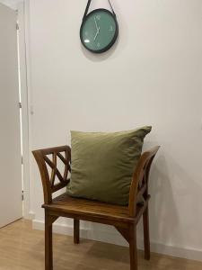 uma almofada verde sentada num banco de madeira com um relógio em Relax Sintra Home - Near Lisbon em Queluz