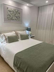 um quarto com uma grande cama branca e um cobertor verde em Relax Sintra Home - Near Lisbon em Queluz