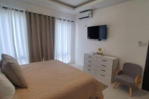 Un dormitorio con una cama y una silla y un televisor. en Paradise Haven at Waterloo, en Kingston
