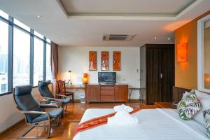 バンコクにあるホテル マーメイド バンコクのベッド、椅子、テレビが備わるホテルルームです。