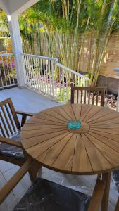 una mesa de madera con 2 sillas y una sombrilla en el porche en Villa Creole alamanda 2 en Petite Île