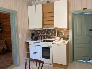 uma cozinha com armários brancos e um forno com placa de fogão em Narvan Maatilamajoitus Helenan Kanat ja Kammarit 