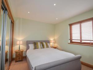 Un dormitorio con una cama blanca y una ventana. en Lossiemouth Bay Cottage, en Lossiemouth