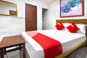 Un dormitorio con una cama con almohadas rojas y una mesa. en OYO Hotel Brazil,Guadalajara,Estadio Jalisco, en Guadalajara