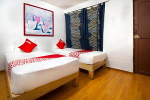 2 camas en una habitación con almohadas rojas en OYO Hotel Brazil,Guadalajara,Estadio Jalisco, en Guadalajara