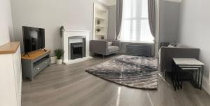 a living room with a television and a couch and a rug at The Princess Flat, Helensburgh. in Helensburgh