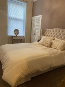 uma grande cama branca num quarto com uma janela em The Princess Flat, Helensburgh. em Helensburgh