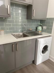 a kitchen with a sink and a washing machine at The Princess Flat, Helensburgh. in Helensburgh