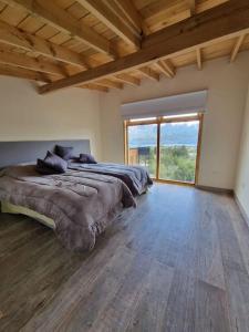 1 dormitorio con cama grande y ventana grande en Lomas Schuss ARG41 en San Carlos de Bariloche