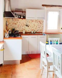 a kitchen with white cabinets and a table with chairs at Villa Ginevri, La casa vacanze immersa nel verde in Mondavio