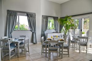 un comedor con mesas, sillas y ventanas en The Shore House, en Hartbeespoort