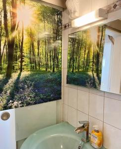 lavabo en el baño con una pintura de un bosque en Helle, grosse, zentrale Wohnung mit Balkon, en Múnich