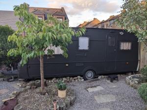 una roulotte nera parcheggiata di fronte a una casa. di Cara Noir a Inverness