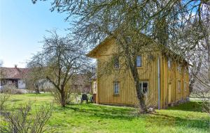une maison jaune dans un champ planté d'arbres dans l'établissement 3 Bedroom Beautiful Home In Ronneby, à Ronneby