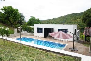 une maison avec une piscine et un parasol rose dans l'établissement Casa Quinta Villa Carolita, à Melgar
