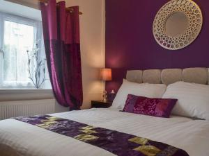 a bedroom with a bed with purple walls and a window at The Snug in Aberaeron