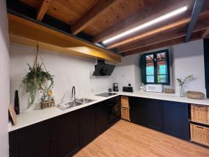 una cocina con armarios negros y fregadero en Rural Lambre by Miramar Stays en A Coruña
