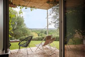 three chairs sitting on a patio outside a glass door at I Carusi Relais in Noto