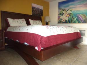 a bedroom with a large bed with a red and white comforter at Glades Motel - Naples in Naples