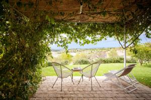three chairs and a table on a brick patio at I Carusi Relais in Noto