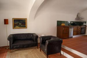 a living room with two leather chairs and a kitchen at TI8-Travessa das Invernas 8 in Évora