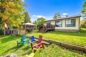 a yard with colorful chairs in front of a house at Cozy Waterfront Cottage, WiFi-Netflix-Dog Friendly in Lanark