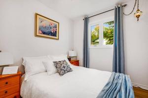 1 dormitorio con cama blanca y ventana en Cozy Waterfront Cottage, WiFi-Netflix-Dog Friendly en Lanark