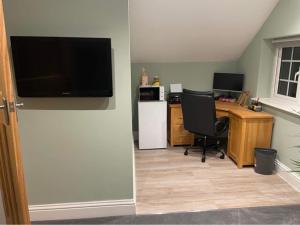 a living room with a desk and a television on a wall at The Up And Over in Northallerton
