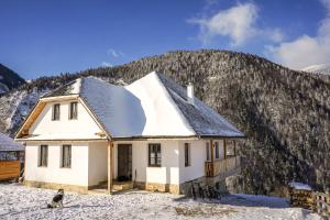 a house in the snow in front of a mountain at Pensiunea Hodăița in Măgura